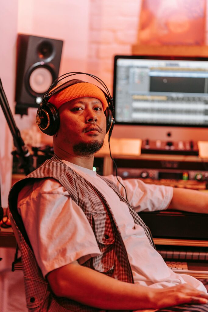 Music producer wearing headphones in a modern studio setting, creating beats.